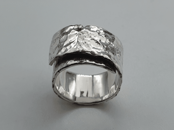 wraparound sterling silver ring with hammered surface and fluid design curved silver band with cratered finish and soft reflection