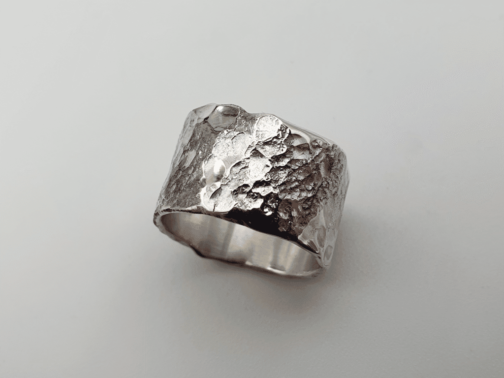 wide statement ring with raw texture and mirror-like silver sheen