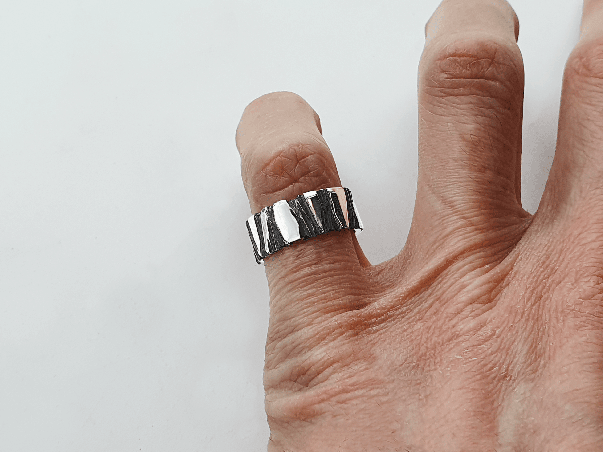 oxidised-silver-ring-fractur-finger modern silver ring with rugged blackened surface – zoomed on finger
